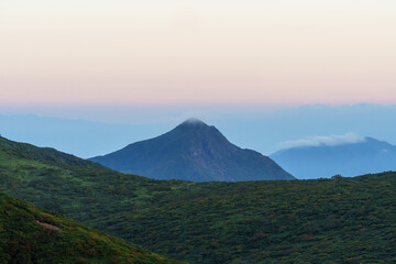 夜明け前の山々の稜線と遠くに霞む山の峰と朝日に照らされて赤くなる空　栃木県那須