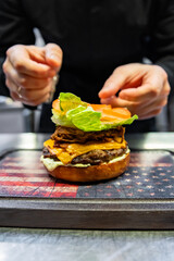 chef hand cooking cheeseburger with vegetables and meat on restaurant kitchen