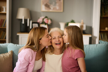 Little daughter and her mother kissing grandmother at home