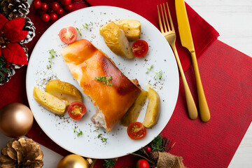 Segovia suckling pig cooked in the oven with apples. Served on a table with Christmas decorations.