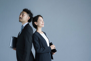 背中合わせのビジネスマンとビジネスウーマン 見上げる 目標や未来を見つめるイメージ 