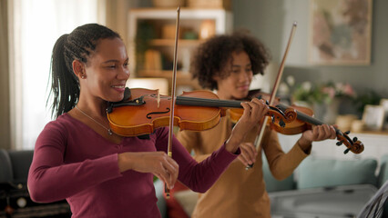 Mother and teenage boy playing violins at home © Stockphotodirectors