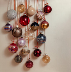 Christmas tree balls in brown burgundy gold black color on a light wall. Balloons hang on a ribbon with a bow.