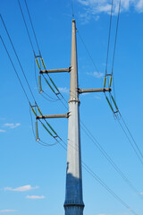 Reinforced concrete power line pole with insulators and wires against the blue sky