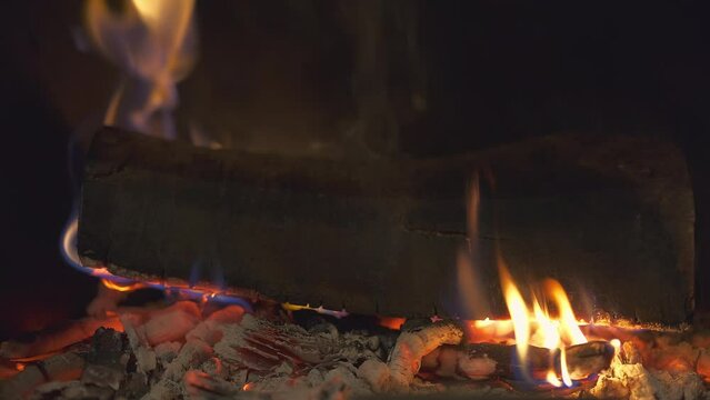 Slowly burning fire in the fireplace close-up, camera movement to the left, 4k footage for a background idea or screensaver about home comfort, real-time video