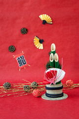 日本の正月　門松、松飾りと扇と竜の文字の凧と水引のデザイン（赤和紙背景））
