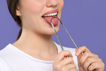 Woman brushing her tongue with cleaner on violet background, closeup