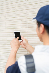 家の外壁の点検をする作業員の男性
