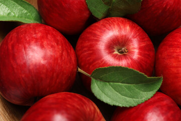 Ripe red apples and green leaves in wooden bowl, top view
