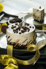 Oreo Cheesecake slice include chocolate, cream, sugar with fork and flowers served in plate isolated on napkin side view of cafe food