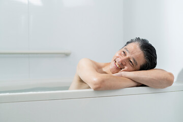 湯船に浸かってリラックスする40代男性