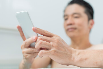 半身浴をしながらスマートフォンで動画を見る40代男性