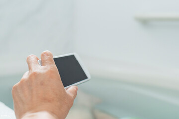 半身浴をしながらスマートフォンで動画を見る40代男性