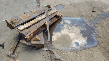 Piece of wood left on the ground near to the puddle