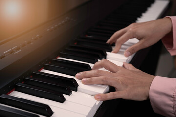 Fototapeta premium Close up senior woman hand with frickle playing electronic paino at ome, relaxing time with music, practice music, learning music at home concept. Light at the coner.