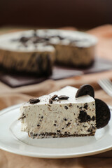 Oreo Cheesecake slice include chocolate, cream, sugar with fork and flowers served in plate isolated on napkin side view of cafe food