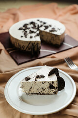 Oreo Cheesecake slice include chocolate, cream, sugar with fork and flowers served in plate isolated on napkin side view of cafe food