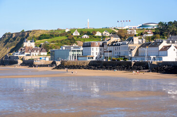 General view of the seafront and beach of Arromanches in Normandy, France, with the D-Day Museum and on the clifftop, the Arromanches 360 cinema and the statue of the Virgin Mary.