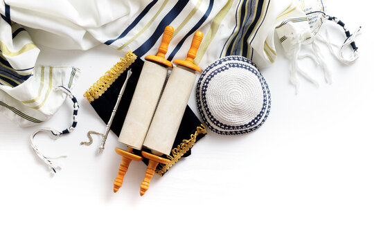 Torah scroll with a pointer, prayer shawl tallit and kippah on a light background