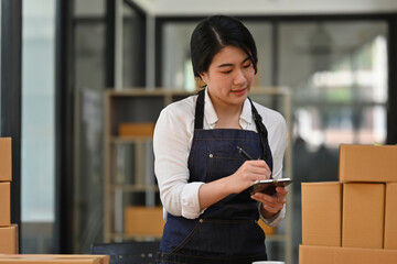 An Online Small business owner verifies correct details and writes the address on a cardboard box