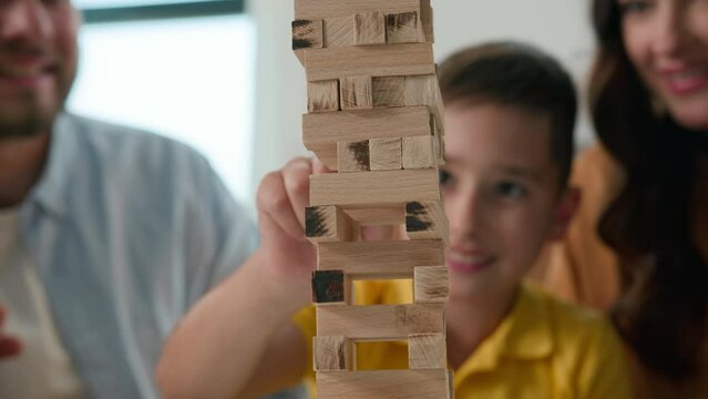 Close-up happy caucasian family mom dad son having fun playing Jenga caring parents play with beloved child boy in intellectual logical board game wooden puzzle spend weekend together enjoying games