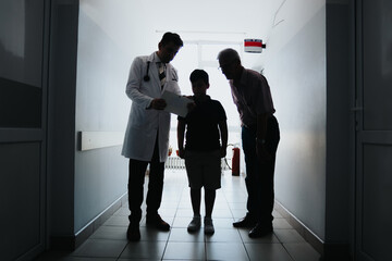 Experienced doctors discussing clinical outcomes while advising a child. Grandfather present. Professional workplace setting. Silhouette photo.