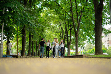 Happy students giving high five after they met each other on a sidewalk after classes