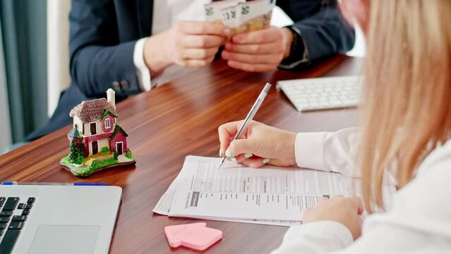 Signing contracts with real estate agents, signing contracts to know the terms of buying and selling homes and real estate. Man counting and giving cash money to a woman, first rent payment