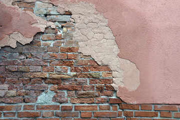 alte, verwitterte Hausmauer aus Backsteinen mit abgebröckeltem Putz