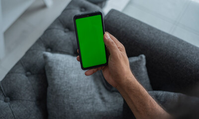 Man is holding a smartphone in front of him . Green screen, copy space and chroma key on smartphone screen.