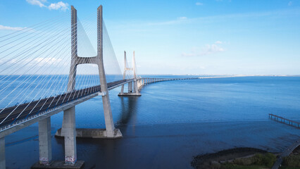 Aerial view of the Vasco da Gama Bridge is a cable-stayed bridge located in the city of Lisbon in Portugal and crosses the Tagus River. It is the second-longest bridge in Europe. - obrazy, fototapety, plakaty