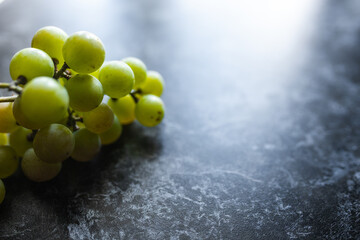 Green organic grapes lie on a dark background. An organic grapes close-up. Fruits on a black background. Berries on a black marble table