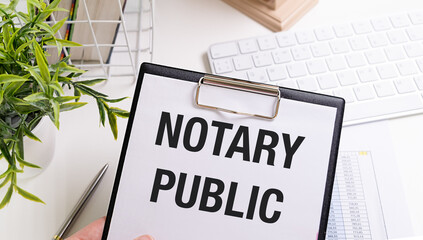 NOTARY PUBLIC is written in a white notepad near a calculator, coffee, glasses and a pen. Business...