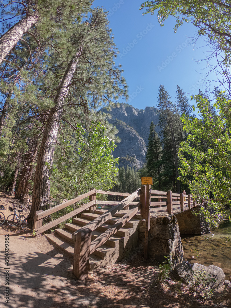 Wall mural a wooden bridge over the merced river with mountains in the background, yosemite national park, cali