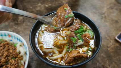 Beef noodles chili sauce served in a bowl on table top view of taiwanese food. Soup beef noodle in...
