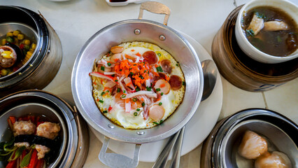 Fried eggs in a small pan with ham, minced pork, spring onion and chinese sausages. Popular Thai Breakfast called Kai Kata.