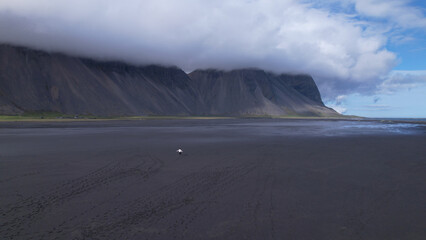 Vestrahorn mountain and Stokksnes beach. Vestrahorn Mountain is located in southeast Iceland near the town of Höfn. Woman walking alone on the black sand beach.
