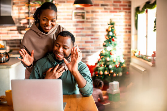 Young African American couple having a video call on a laptop at their home decorated for the Christmas and new year holidays