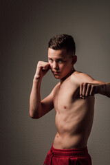 Obraz premium A teenage boxer athlete is training to box on dark background. Aggressive sport