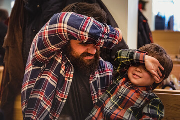Guy with long beard and a boy play with covered eyes indoor. long bearded man and a child play...