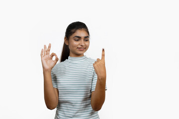 Young Indian girl smiling and pointing after casting her vote, isolated on a white background