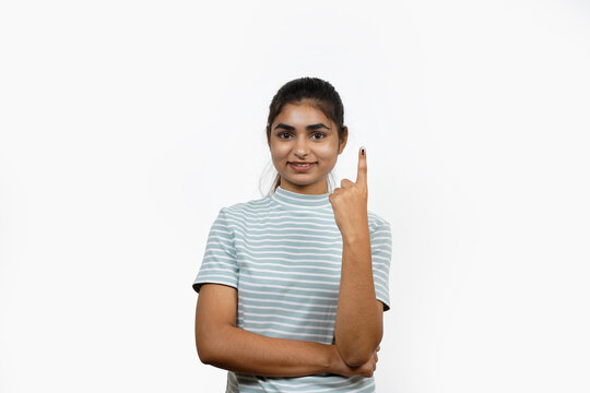 Young Indian girl smiling and pointing after casting her vote, isolated on a white background