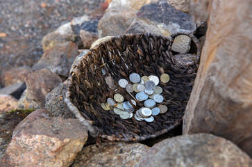 Coins in a bowl on a rustic wooden table, top view. Money concept