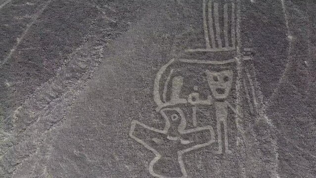 Small human figures and bird of the Nazca Lines geoglyphs made in the soil of the Nazca Desert Aerial video