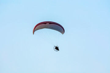 motorized para-glider against isolated blue sky 