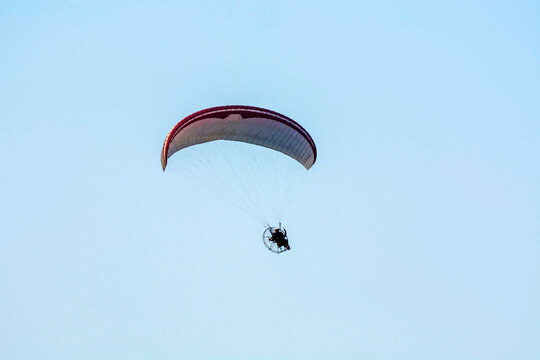 motorized para-glider against isolated blue sky 