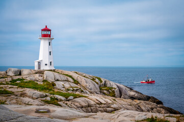 Iconic Peggy's Cove Lighthouse with red fisherman boat, Nova Scotia, Canada. Photo taken in September 2023. - obrazy, fototapety, plakaty