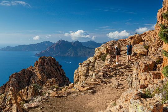zwei  Wanderer laufen in der Calanche einer bizarre Felsenlandschaft an der Suedkueste des Golfs von Porto im Regionalen Naturpark Korsika Frankreich Europa
