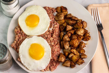 two fried eggs  with corn beef hash and home fries