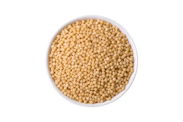 Raw ptitim pasta in a ceramic bowl on a dark concrete background